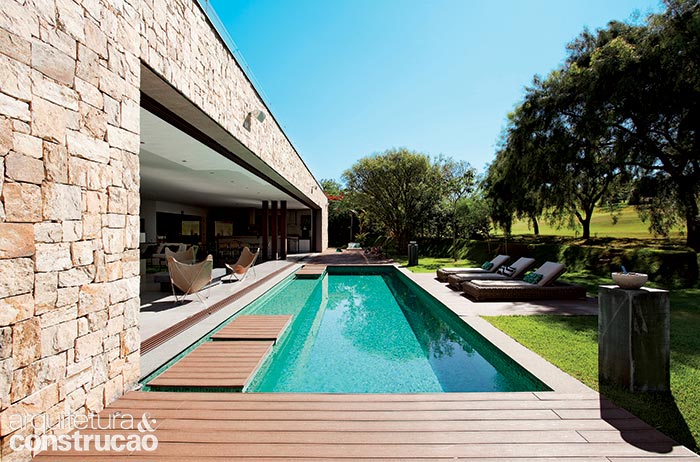 Esta foto revela a extensão de mais de 20 m do vão da sala. Com 3,80 x 7 m, a piscina leva plaquetas de 20 x 20 cm de pedra hijau (Palimanan). Perto do estar, surgem as pisadas flutuantes revestidas com o mesmo deck plástico (Allpex Madeira Plástica) de toda a área externa. (Marco Antonio)